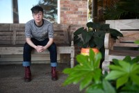 Charlie Apple sits on a bench outside his home.
