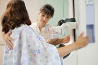 A photo shows a medical professional giving a woman a mammogram screening.