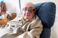 A photo shows Melvin Zax sitting at home.