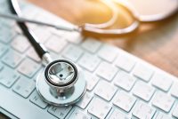 A photo shows a stethoscope resting on a computer keyboard.