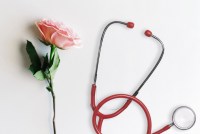 A photo illustration shows a pink rose resting next to a stethoscope.
