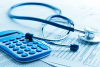 A photo of a stethoscope and calculator resting on top of paperwork.
