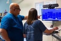 Lalit Bajaj points to a computer screen, standing beside fellow emergency physician Julia Fuzak Freeman.