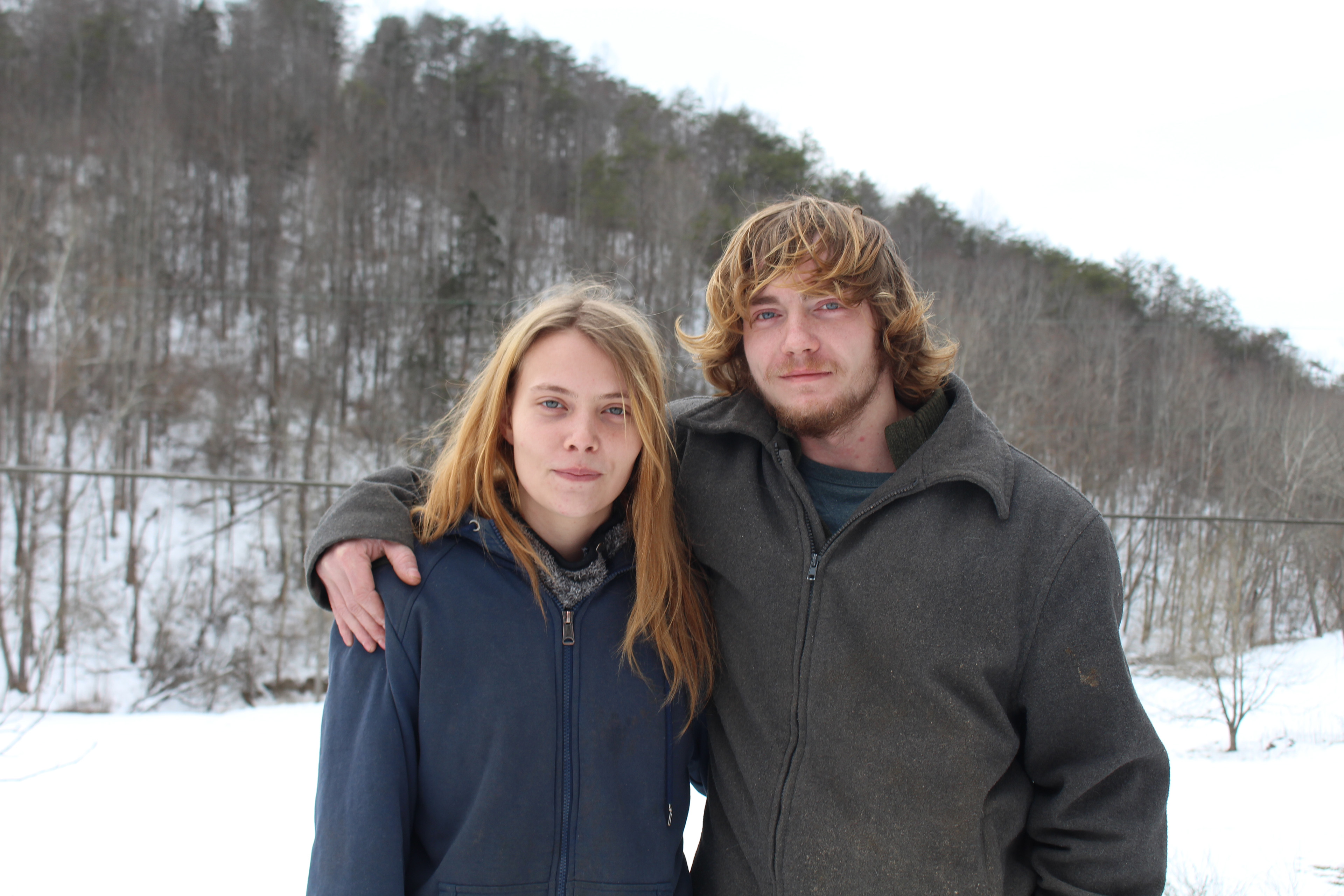 A man and woman, both wearing jackets, stand with arms around each other and pose for a photo